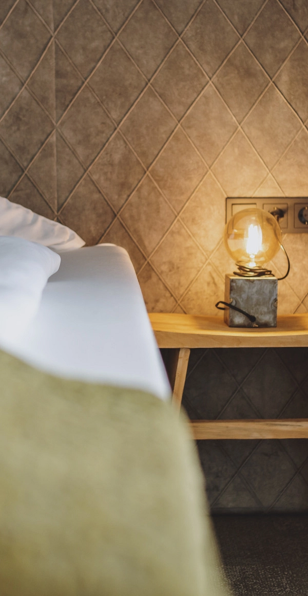 Detailaufnahme eines Bettes mit Nachttischlampe