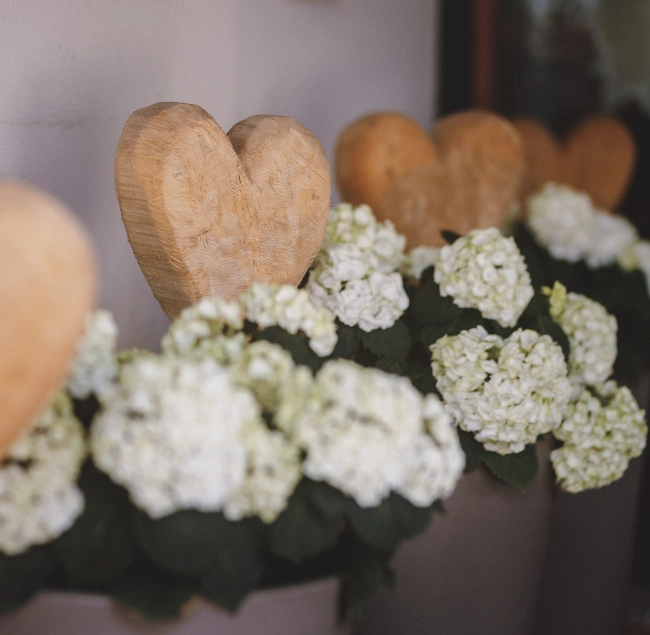 Holzherzen und weiße Blumen arrangiert in einer Dekoration