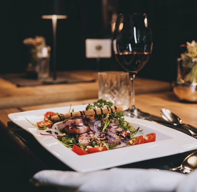 Gourmetgericht auf einem weißen Teller mit Rotwein