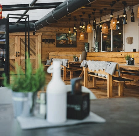 Innenansicht eines Restaurants mit Holztischen und Lampen