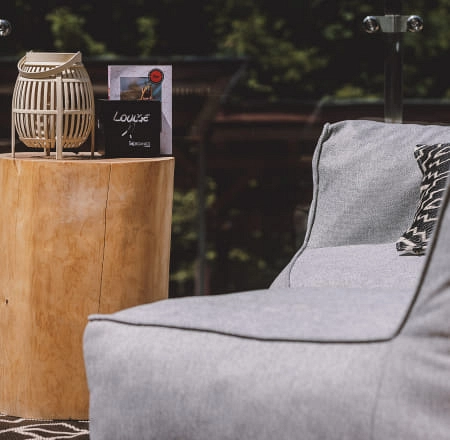 Holztisch mit Laterne und Lounge-Buch auf einem Sofa