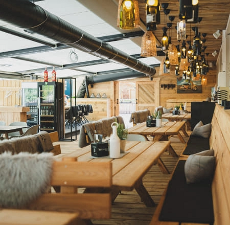 Innenraum eines gemütlichen Restaurants mit Holztischen und Lampen