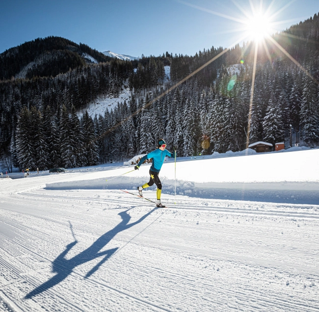 Cross-country skier on a snowy trail with sun shining