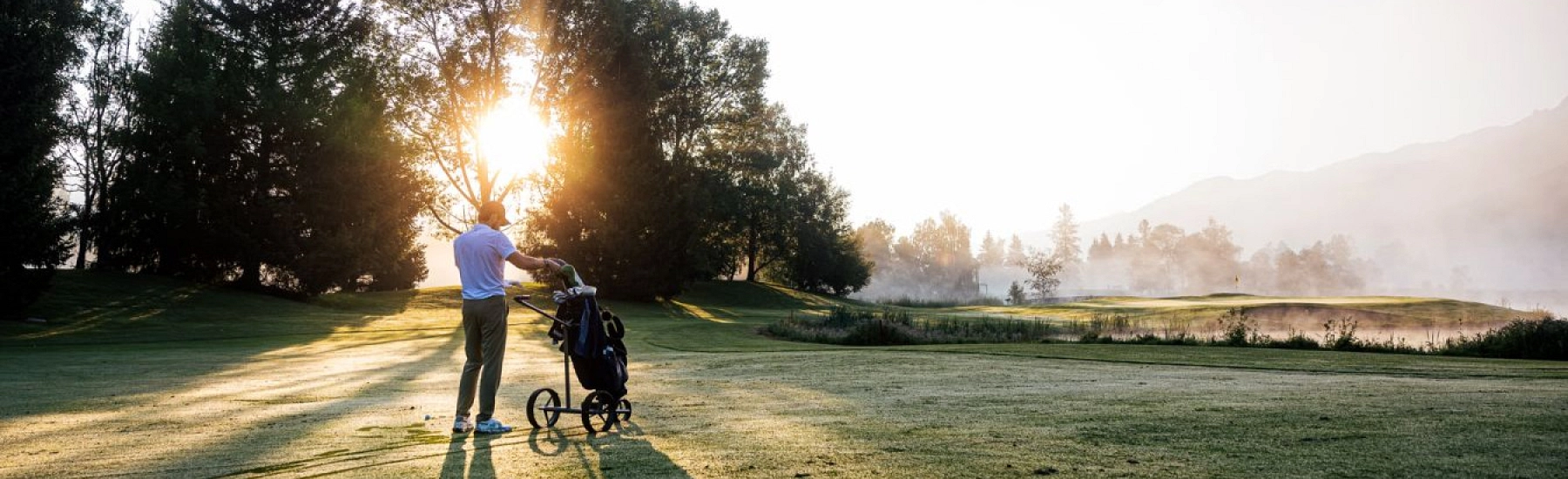 Golfer mit Trolley vor malerischer Kulisse in Zell am See